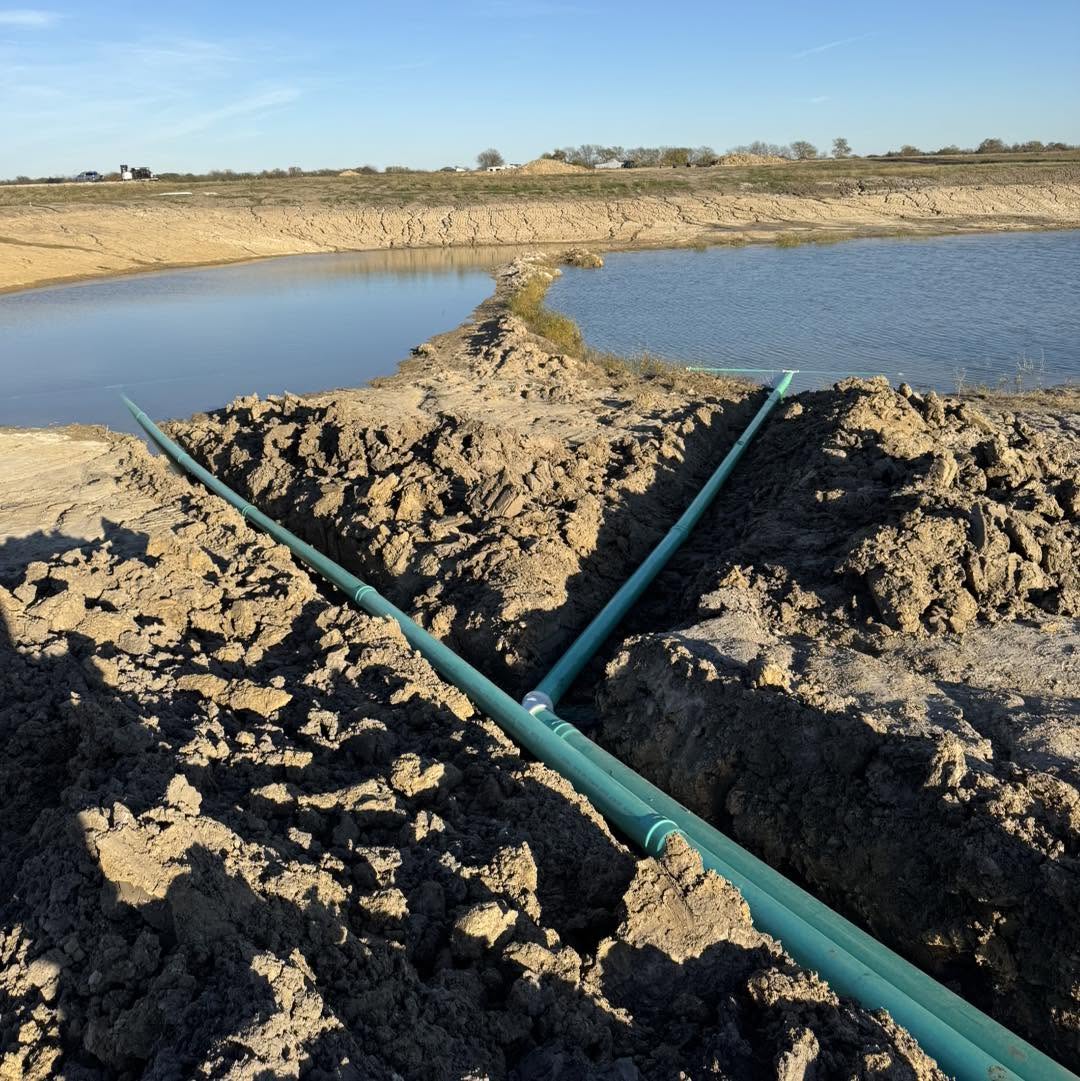 Water management piping installed through the dam of a Texas pond